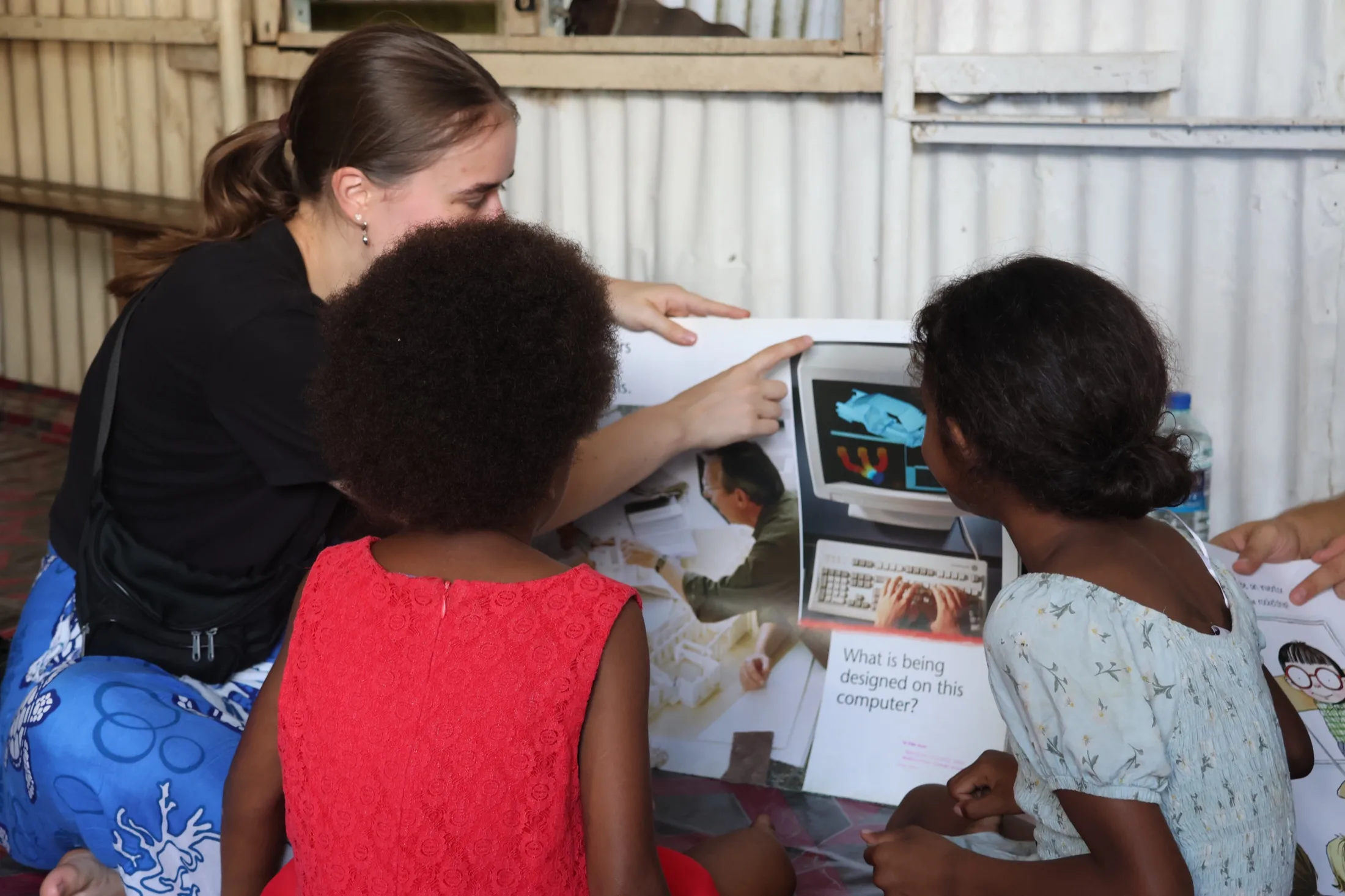 A Vunilagi volunteer reads with children during a community reading session